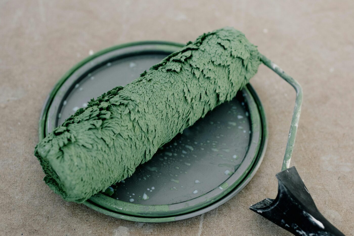 DIY painting essentials: a paint roller and green paint on a table.