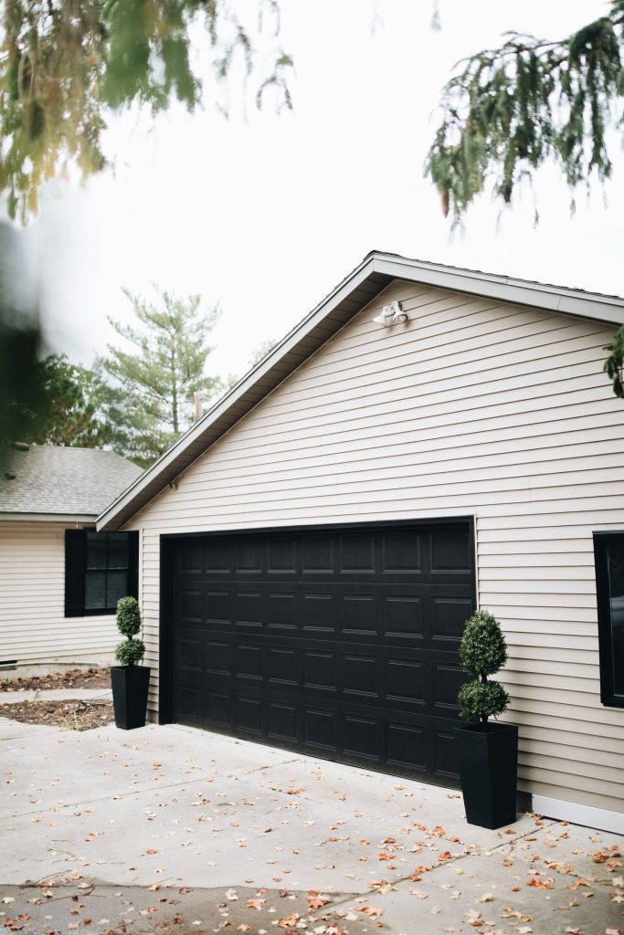 A garage door painted black on a white home