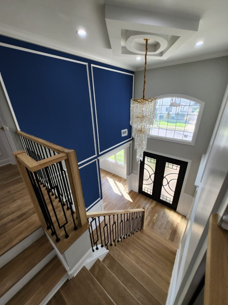 A stairwell with a deep blue feature wall and white trim after an interior repaint